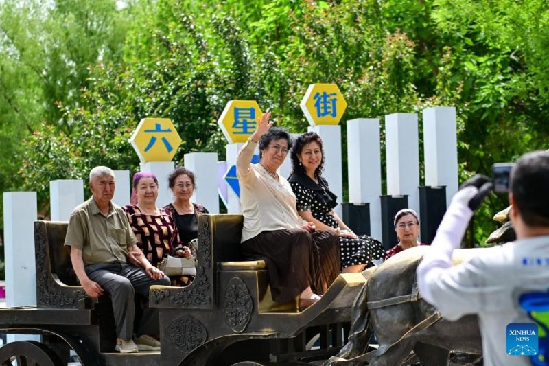 Τουρίστες ποζάρουν για φωτογραφίες στην κεντρική πλατεία της οδού Λιοσίνγκ στην πόλη Γινίνγκ, της αυτόνομης νομαρχίας Ιλί Καζάκ, στην αυτόνομη περιοχή των Ουιγούρων της επαρχίας Σιντζιάνγκ της βορειοδυτικής Κίνας, στις 12 Μαΐου του 2024. (Xinhua/Ding Lei)