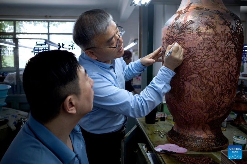  Ο Τζονγκ Λιάνσενγκ και ένας τεχνίτης εφαρμόζουν φιλιγκράν σε έργα τέχνης Tζινγτκαϊλιέν στο εργοστάσιο σμάλτου του Πεκίνου,  στις 15 Μαΐου του 2024.