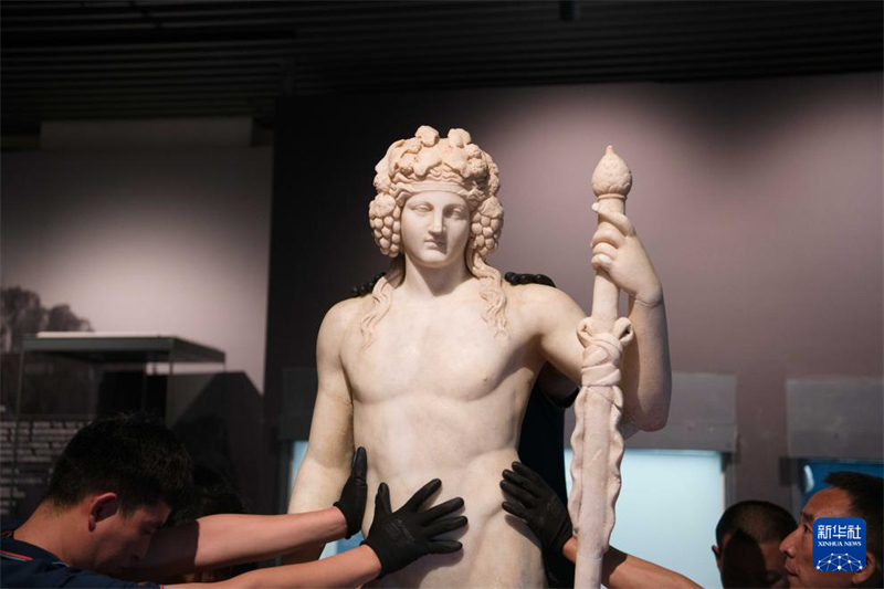 Προσωπικό τοποθετεί αρχαία ελληνικά αντικείμενα στο περίπτερο της έκθεσης, στις 2 Ιουλίου. (Φωτογραφία / Xinhua)