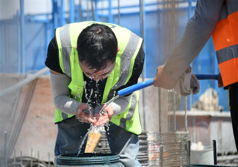 Εργαζόμενος σε εξωτερικό χώρο δροσίζεται ρίχνοντας νερό στο πρόσωπό του σε ένα εργοτάξιο στην Σιάν μια ζεστή καλοκαιρινή μέρα, στην βορειοδυτική επαρχία Σανσί της Κίνας, στις 13 Ιουνίου 2024. (Φωτογραφία / Xinhua)